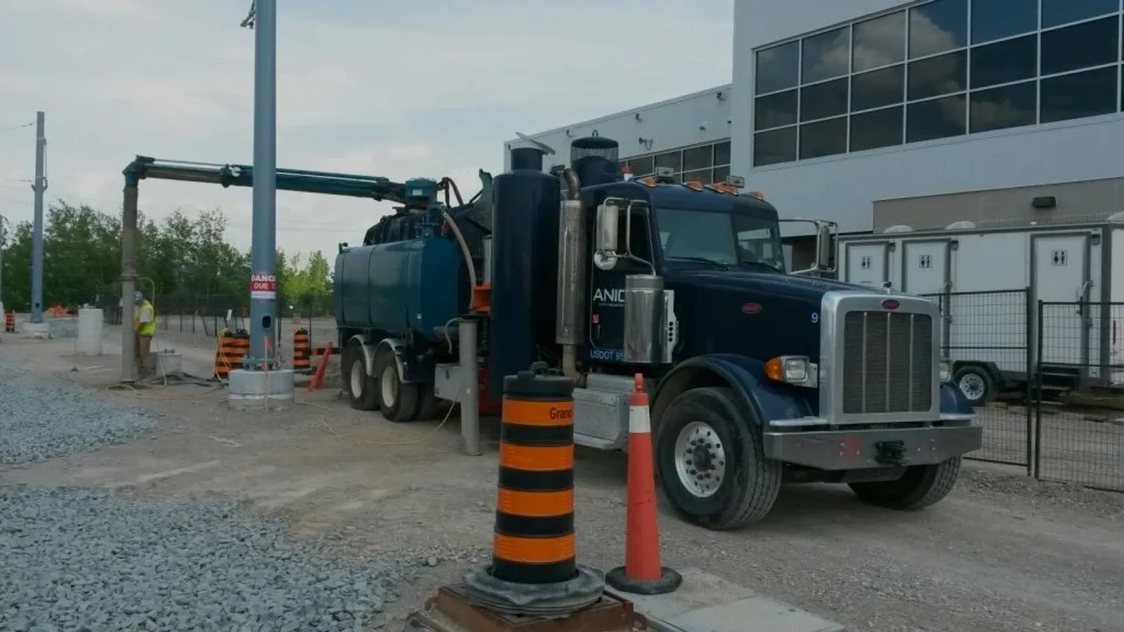 ANIC hydro vac rig with boom deployed, excavating around a live utility pole on an active Ontario site